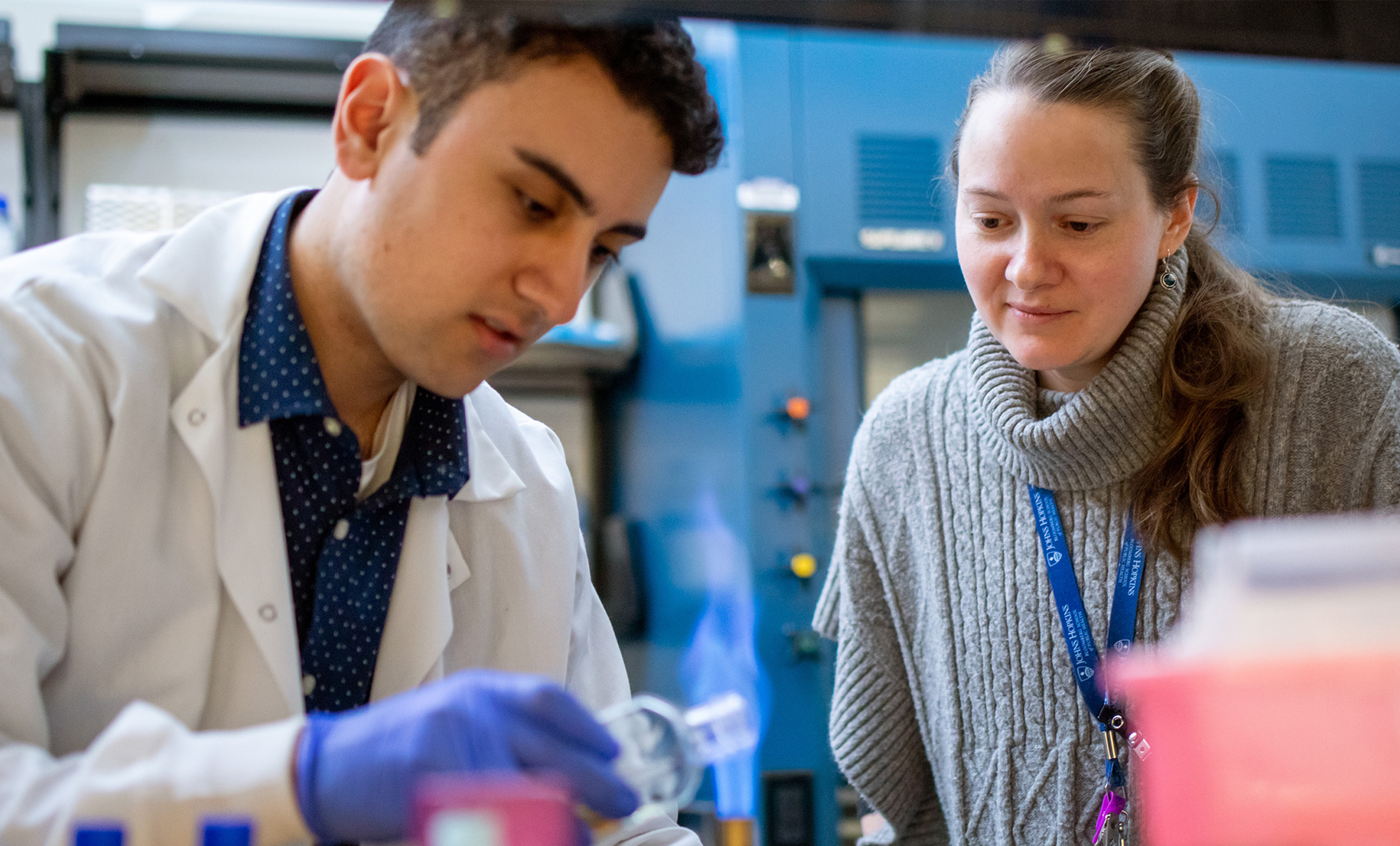 Kim Davis observes as MMI PhD student Parsa Farhang uses a bunsen burner before working with media culture.