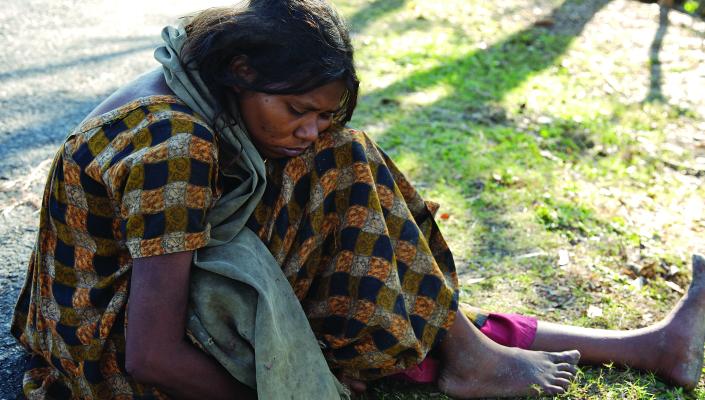 a woman sits on the ground with a blanket wrapped around her