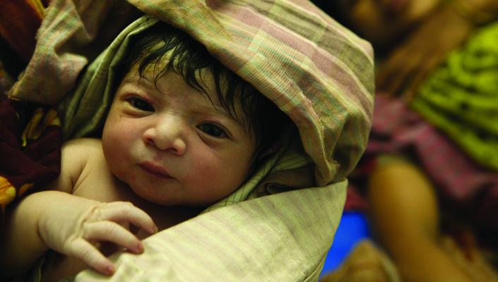 a newborn baby swaddled in a tan and red plaid blanket