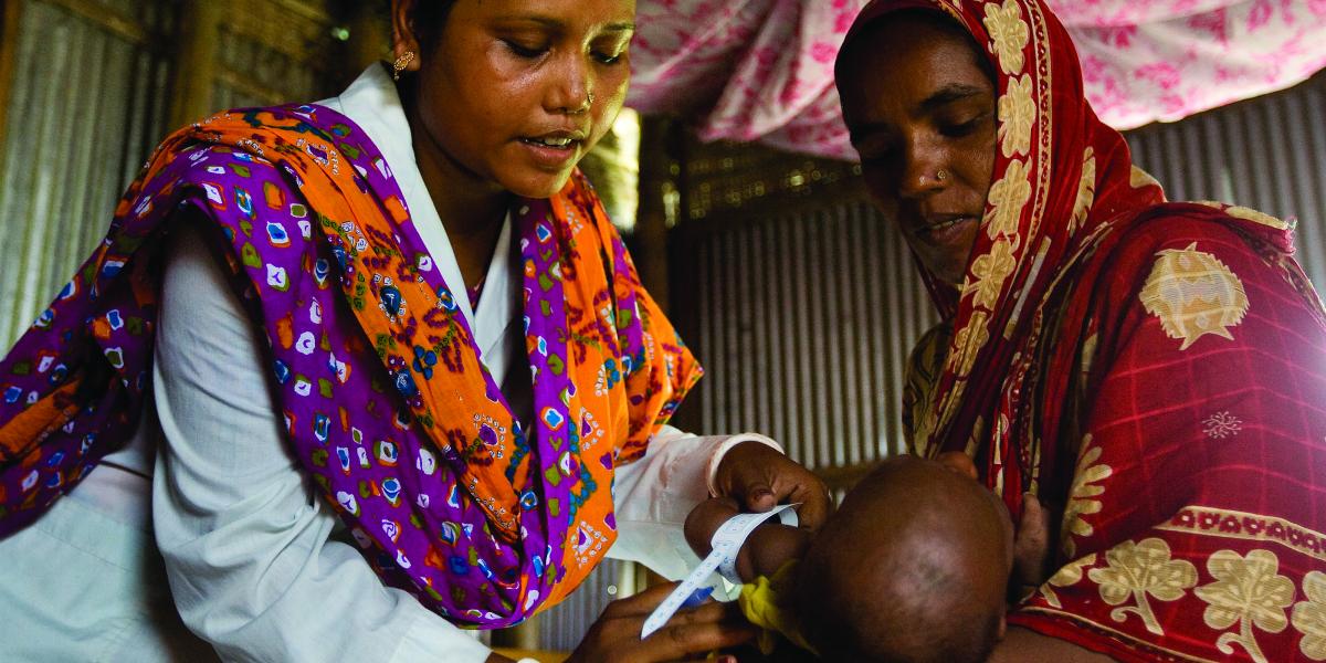 JiVitA interviewer Ripu Rani measures a child's arm while her mother looks on