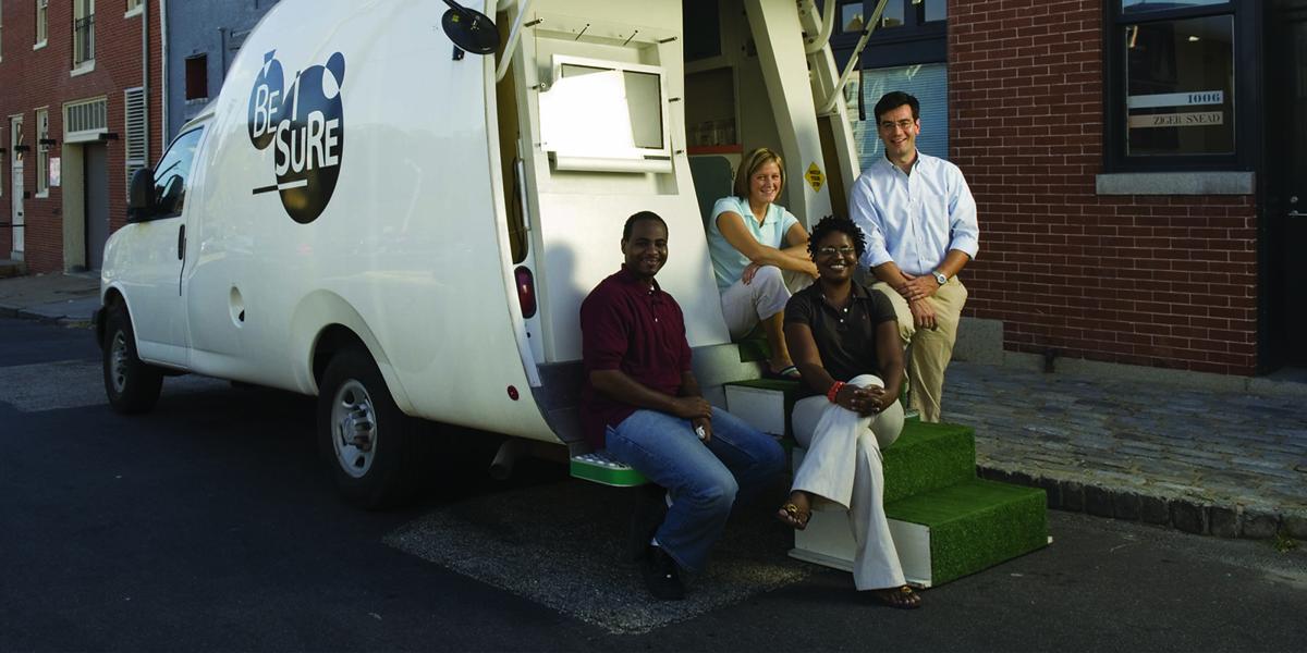 McCay Morifay, Martha Hilton, Frangiscos Sifakis, and Keba Robinson sit and stand at the back of the BESURE van.