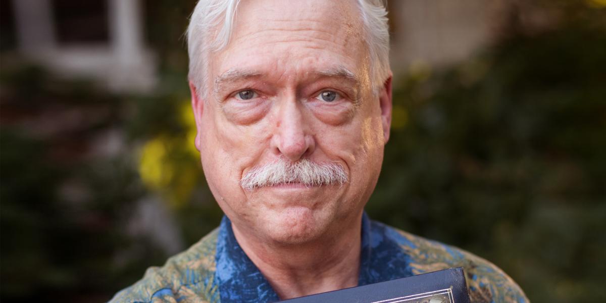 Chris Camp holds a photo album with the words Chris & Jack on the cover