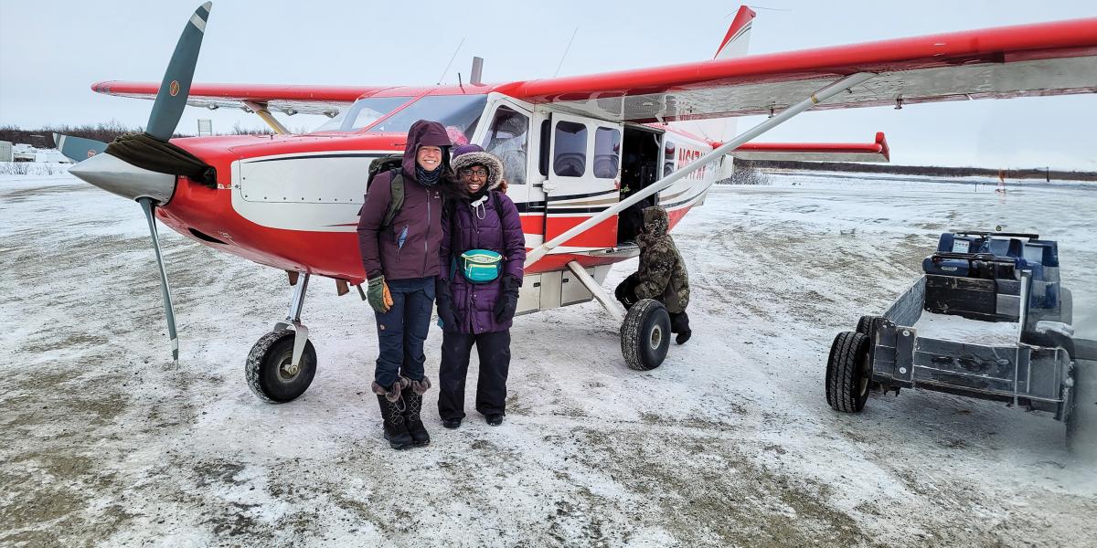 Mary McQuilkin and Bionca Davis in front of a plane in Alaska.