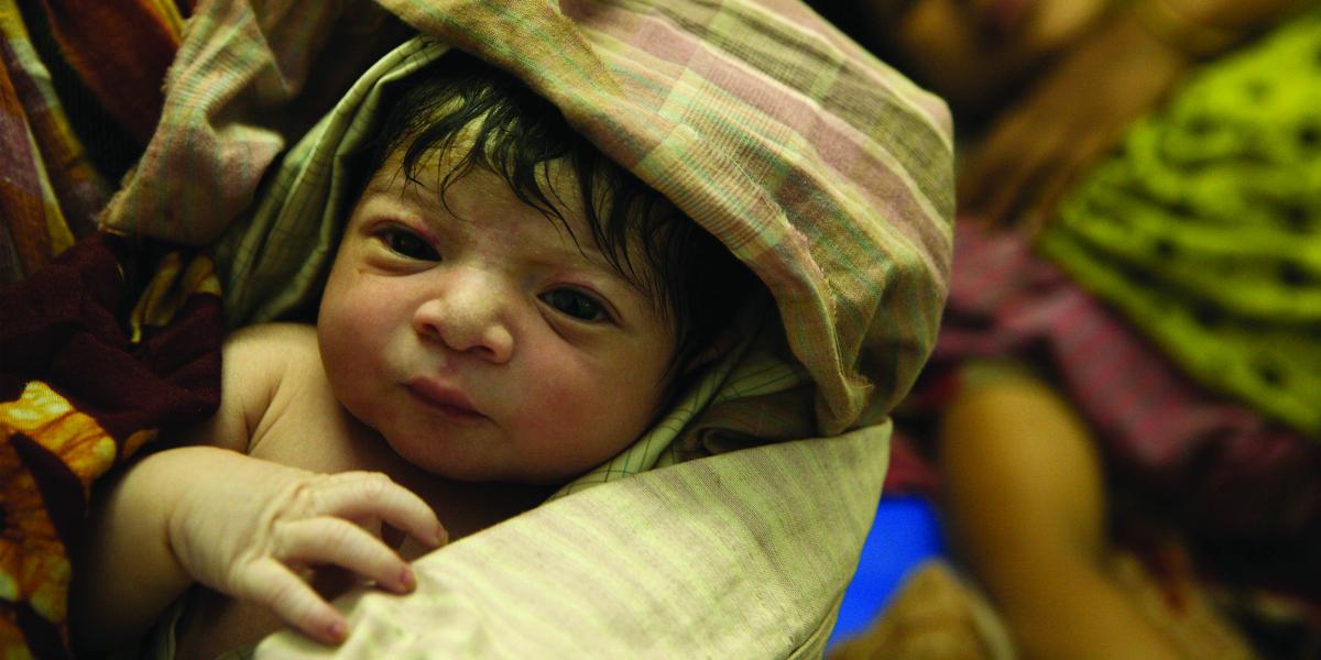 a newborn baby swaddled in a tan and red plaid blanket