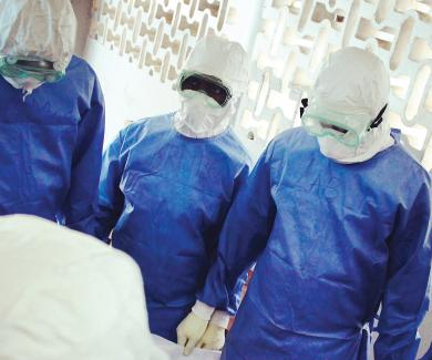 4 researchers wearing blue PPE and goggles