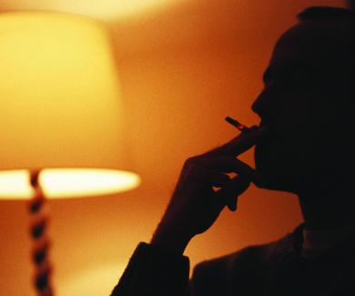 silhouette of a person smoking in the light of a living room lamp