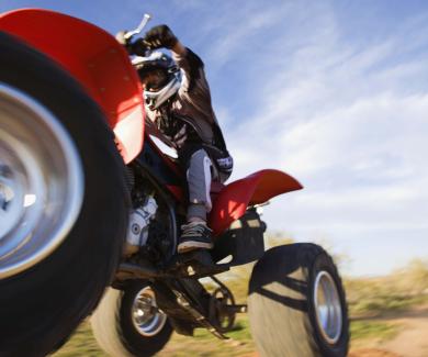 photo of a young person wearing a helmet and riding an airborne ATV