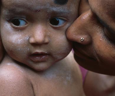 a mother holds and kisses the cheek of her infant