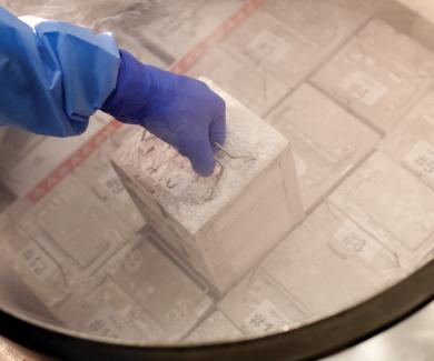 a gloved hand lifts a frozen sample from one of the biorepository's cylinders