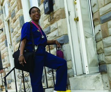 Community health worker Paige Bailey stands on the stoop of a Baltimore rowhome