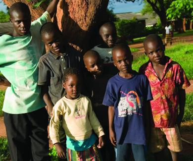 a man and 6 children stand in the shade of a tree in Macha, Zambia