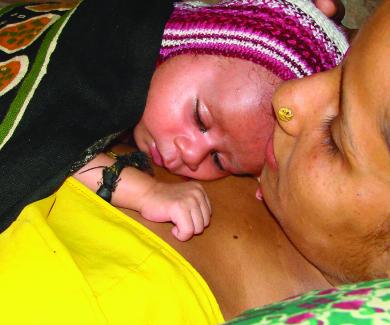 A mother holds her newborn to her chest for skin-to-skin contact