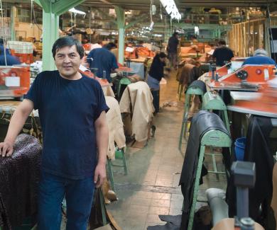 A man stands on a busy textile plant workroom floor.